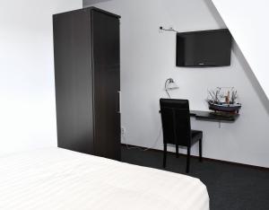 a bedroom with a bed and a desk and a tv at Hotel Royal in IJmuiden