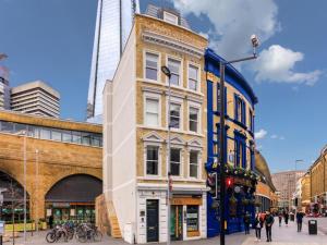 a tall building in a city with people walking on a street at London Bridge Boutique by Viridian Apartments in London