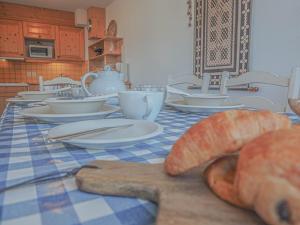 una mesa con un mantel azul y blanco con una barra de pan en Les Epilobes 3, en Landry