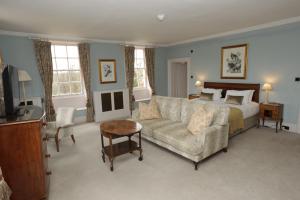 a bedroom with a bed and a couch and a television at Chicheley Hall in Milton Keynes