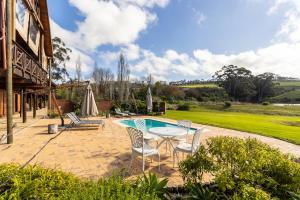 un patio con mesa, sillas y piscina en The Log Cabin Lodge en Stellenbosch