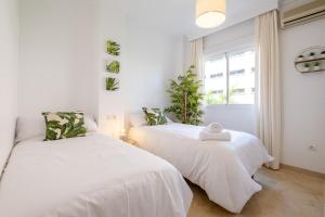 2 camas en una habitación blanca con ventana en Garden & Beach - Torremolinos en Torremolinos