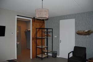 a living room with a book shelf and a chair at Hoeve de Heemser Parel in Heemserveen