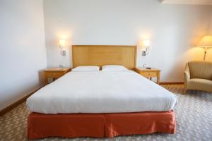 馬尼拉的住宿－The Linden Suites，一间卧室配有一张大床和一把椅子