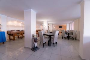 uma sala de jantar com mesas e cadeiras e um piano em Corfu Maris em Benitses