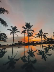 a sunset with palm trees and a pool of water at Kizikula - Boutique Hotel in Kizimkazi