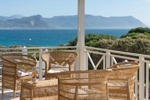 a group of wicker chairs on a balcony with the ocean at Boulders Beach Hotel, Cafe and Curio shop in Simonʼs Town