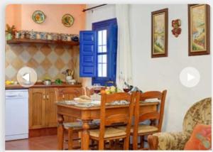 a kitchen with a table and chairs and a blue shutter at Villa Damara con piscina privada in Nerja