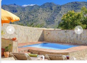 a swimming pool with two chairs and an umbrella at Villa Damara con piscina privada in Nerja