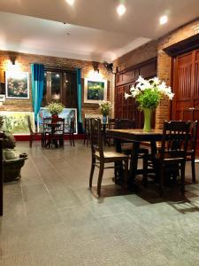 a dining room with a table with chairs and flowers at Calm House Hotel Hoi An 1 in Hoi An
