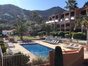 a resort with a swimming pool with lounge chairs and a building at Plage de Miramar in Théoule-sur-Mer