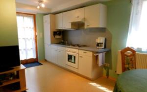 cocina con armarios blancos y fogones en Ferienwohnung - Zimmervermietung Ringelmann, en Dettelbach