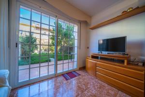 uma sala de estar com uma televisão de ecrã plano e uma janela grande em HomeHolidaysRentals Charme - Costa Barcelona em Santa Susanna