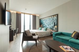 DUPARC Contemporary Suites في تورينو: غرفه فندقيه بسرير واريكه