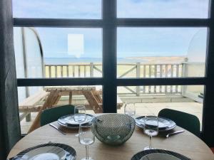 - une table avec des verres à vin et une vue sur l'océan dans l'établissement La mer vue d'en haut , duplex à la naturelle sur la côte d'opale, à Wimereux