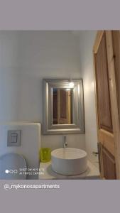 y baño con lavabo blanco y espejo. en Mykonos Rooms en Agios Stefanos
