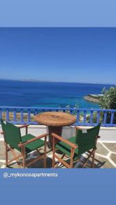 einen Tisch und Stühle mit Meerblick im Hintergrund in der Unterkunft Mykonos Rooms in Agios Stefanos