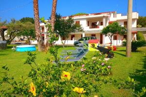 a yard with a house with palm trees and flowers at Villa Eulalia in Capo Vaticano