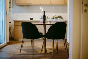una cocina con 2 sillas y una mesa con una botella de vino en Apartman Gold en Slavonski Brod