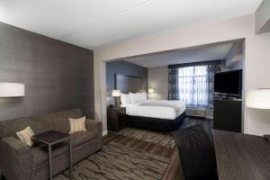 a hotel room with a bed and a couch at La Quinta by Wyndham Raleigh Downtown North in Raleigh