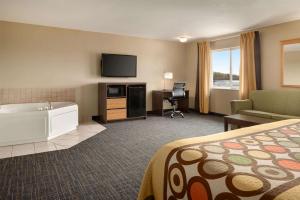 a hotel room with a bed and a couch and a television at Super 8 by Wyndham Sioux Falls in Sioux Falls
