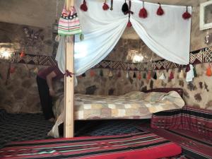 a woman standing next to a bed in a room at Petra Cottage in Al Ḩayy