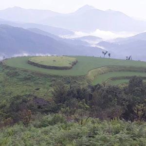 a golf course on a hill with mountains in the background at Vamoose Mudra Midtown in Kalasa