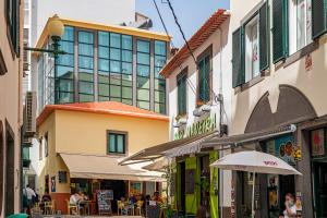 フンシャルにあるPelourinho Apartments by An Island Apartの建物・テーブル・傘が並ぶ街道