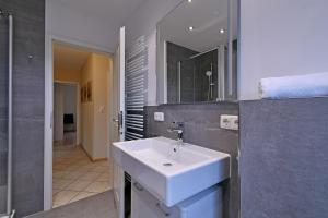 a bathroom with a white sink and a mirror at Appartement-Blume-PCH-16B in Scharbeutz +31 photos