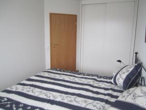 a bedroom with a bed with a blue and white blanket at Appartement-Konsulweg-KON-375 in Scharbeutz