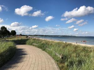 a brick path next to a beach with the ocean at Appartement-Konsulweg-KON-375 in Scharbeutz