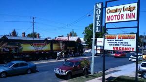 a sign for a motor inn on a street with cars at Country Lodge Motor Inn in Bathurst
