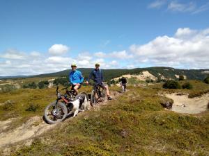 three people riding bikes on a hill with a dog at Casa Bike in Punta Arenas