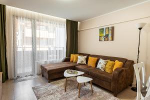 a living room with a brown couch and yellow pillows at Апартамент В4 in Velingrad