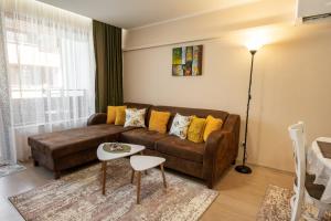 a living room with a brown couch and yellow pillows at Апартамент В4 in Velingrad