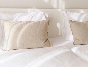 ein Bett mit weißer Bettwäsche und Kissen darauf in der Unterkunft Hotel Zonne in Noordwijk aan Zee