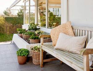 un banc installé sur une terrasse couverte avec des plantes en pot dans l'établissement Hotel Zonne, à Noordwijk aan Zee
