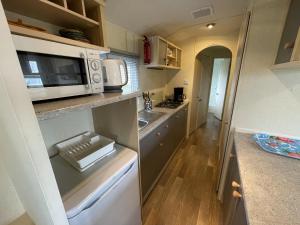 a small kitchen with a microwave and a sink at Beach Resort Nieuwvliet Bad - 274 in Nieuwvliet