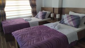 two beds in a hotel room with purple sheets at Serbona apartment in Kladovo