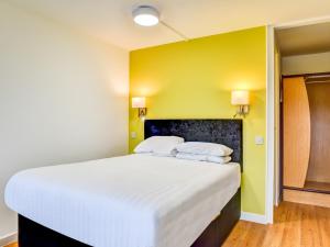 uma cama grande num quarto com uma parede amarela em The Hotel Rafiya, Redditch em Redditch