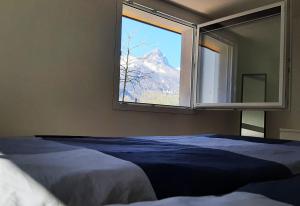 a bedroom with a window with a mountain view at Haus Melchaazopf in Giswil