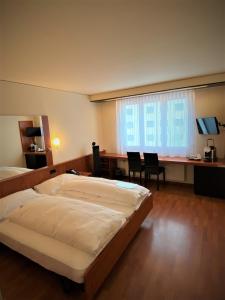 a bedroom with a bed and a desk and a window at Hotel Arte Spreitenbach in Spreitenbach