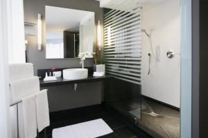 a bathroom with a sink and a shower with a mirror at Boston Hotel HH in Hamburg