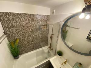Un baño con bañera, lavabo y espejo. en Loft Apartman X. ker., en Budapest
