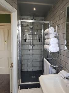 a bathroom with a shower and a sink and towels at Afallon Townhouse Gwynedd Room in Dolgellau