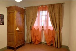 a window with orange curtains and a wooden cabinet at Agriturismo le Bartaline in Pieve di Panzano