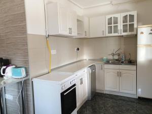 a kitchen with white cabinets and a sink and a refrigerator at Gabi Szálló I. in Poroszló
