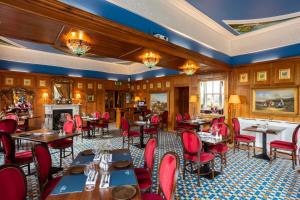 a restaurant with red chairs and tables and a fireplace at Scholars Townhouse Hotel in Drogheda