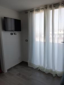 Habitación con cortinas blancas y TV de pantalla plana. en Il rifugio degli artisti en Nápoles