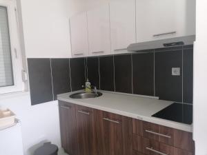 a kitchen with a sink and black and white cabinets at Apartmani Nana Sokobanja in Soko Banja